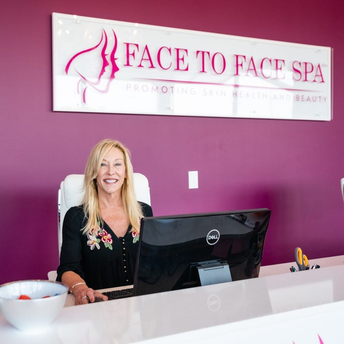 A Face to Face spa franchis owner sitting at reception in front of a computer.