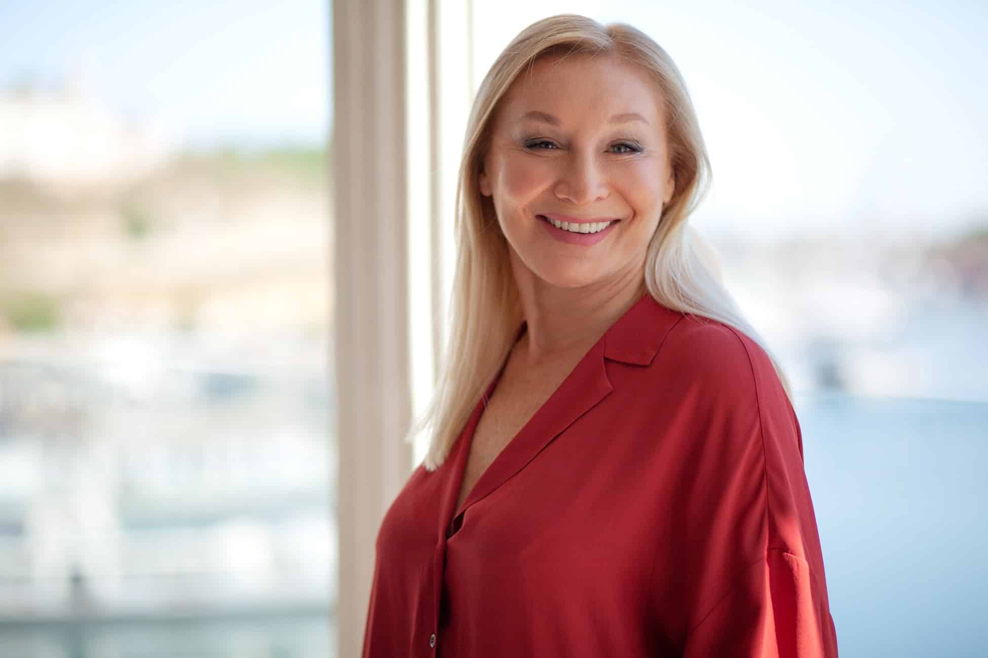 Portrait of a beautiful smiling middle-aged woman in a business casual red silk top.