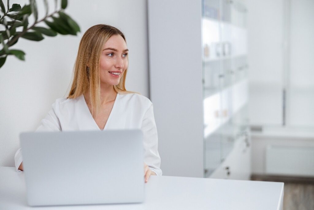 A confident woman smiling with a laptop on her table